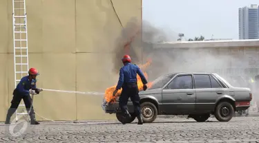 Personel menyelamatkan kebakaran sebuah mobil saat demostrasi kemampuan dalam acara Upacara Perayaan Ulang Tahun Pemadam Kebakaran (Damkar) ke-98 di Lapangan Silang Monas Selatan, Jakarta Pusat, Rabu (1/3). (Liputan6.com/Immanuel Antonius)