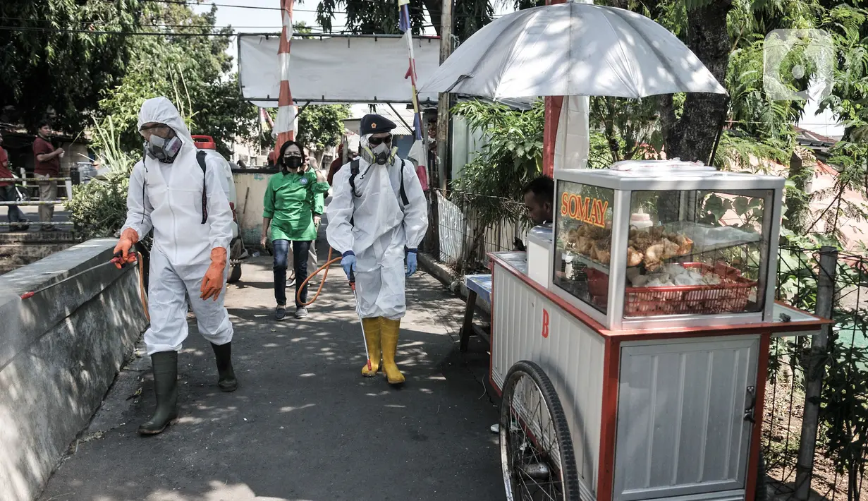 Petugas Palang Merah Indonesia (PMI) Jakarta Timur berpakaian APD menyemprotkan disinfektan di permukiman Kampung Tengah, Kramat Jati, Minggu (23/8/2020). Penyemprotan sebagai langkah sterilisasi permukiman setelah warga di Kampung Tengah dilaporkan terpapar Covid-19. (Liputan6.com/Iqbal Nugroho)