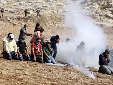 Pengunjuk rasa Palestina melaksanakan salat di tengah tembakan gas air mata tentara Israel di dekat desa Beit Dajan, Palestina (9/10/2020). Insiden terjadi ketika pengunjuk rasa menggelar aksi memprotes pencaplokan tanah yang dilakukan Israel untuk perluasan permukiman Yahudi. (AFP/Jaafar Ashtiyeh)
