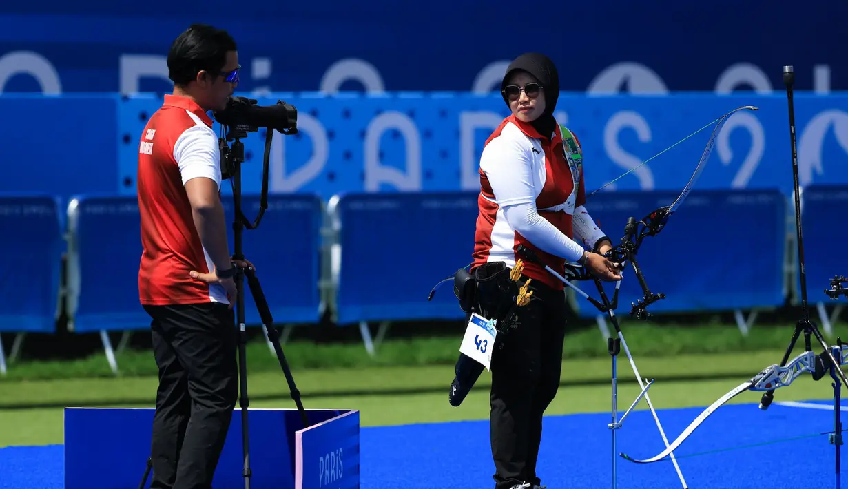 <p>Pelatih Denny memberi masukan kepada atlet panahan putri Indonesia, Syifa Nurafifah Kamal saat menghadapi wakil India, Bhajan Kaur pada babak 64 besar nomor individual putri Olimpiade Paris 2024 di Les Invalides Arena, Paris, Selasa (30/7/2024). Syifa Nurafifah Kamal kalah 3-7. (Dok. NOC Indonesia/Naif Muhammad Al'as)</p>