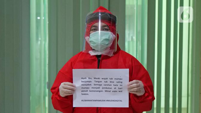 Perawat Alfina Damayanti (28) menyampaikan pesan lewat sebuah tulisan saat di RSUD Pasar Minggu, Jakarta, Jumat (22/5/2020). Sejumlah garda terdepan Covid-19 menyampaikan pesan lewat sebuah tulisan. (Liputan6.com/Herman Zakharia)