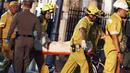 Petugas membawa tubuh korban ledakan bom motor di luar Kuil Erawan di pusat kota Bangkok, Thailand, Senin (17/8/2015). Bom motor tersebut diketahui telah menewaskan sekitar 27 warga. (REUTERS/Athit Perawongmetha)