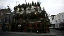 Pejalan kaki melintas di depan bangunan bar The Churchill Arms di London, Inggris, 20 Desember 2016. Pemilik bar tersebut menghabiskan dana sebesar Rp502 juta untuk hiasan pohon natal dan Rp419 juta untuk karangan bunga. (REUTERS/Neil Hall)