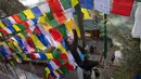 Seorang pria memasang bendera warna-warni atau yang disebut lungta pada hari ketiga Tahun Baru Tibet di Dharmsala, India (18/2). Bendera doa itu merupakan barang yang sakral sekaligus suvenir unik yang seringkali dibawa turis. (AP/Ashwini Bhatia)