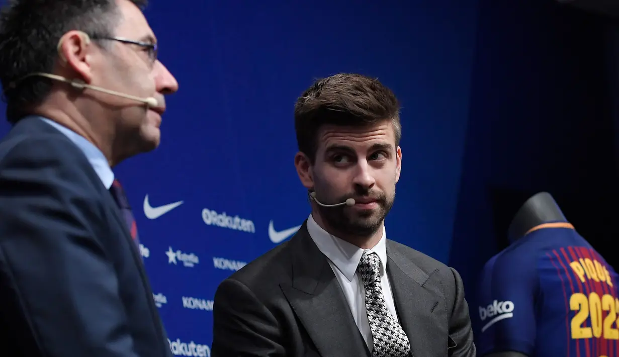 Bek Barcelona, Gerard Pique menyimak Presiden Barcelona FC, Josep Maria pada konferensi pers pengumuman resmi perpanjangan kontraknya di stadion Camp Nou, Senin (29/1). Bek timnas Spanyol itu meneken kontrak baru hingga 30 Juni 2022. (LLUIS GENE/AFP)