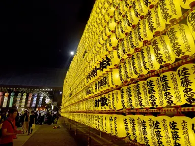 Sejumlah pengunjung melihat lentera yang memeriahkan Festival Mitama di Kuil Yasukuni, Tokyo, Jepang, (13/7). Sekitar 30.000 lentera menerangi daerah terseubt untuk mengenang korban perang.  (AFP Photo/Toru Yamanka)