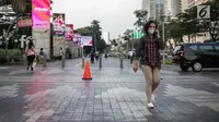 Seorang wanita berjalan mengenakan masker pelindung untuk menghindari polusi udara buruk di Jakarta, Rabu (17/7/2019). Dinkes DKI menyarankan masyarakat untuk menggunakan masker saat beraktivitas untuk mencegah dampak polusi udara pada tubuh. (Liputan6.com/Faizal Fanani)