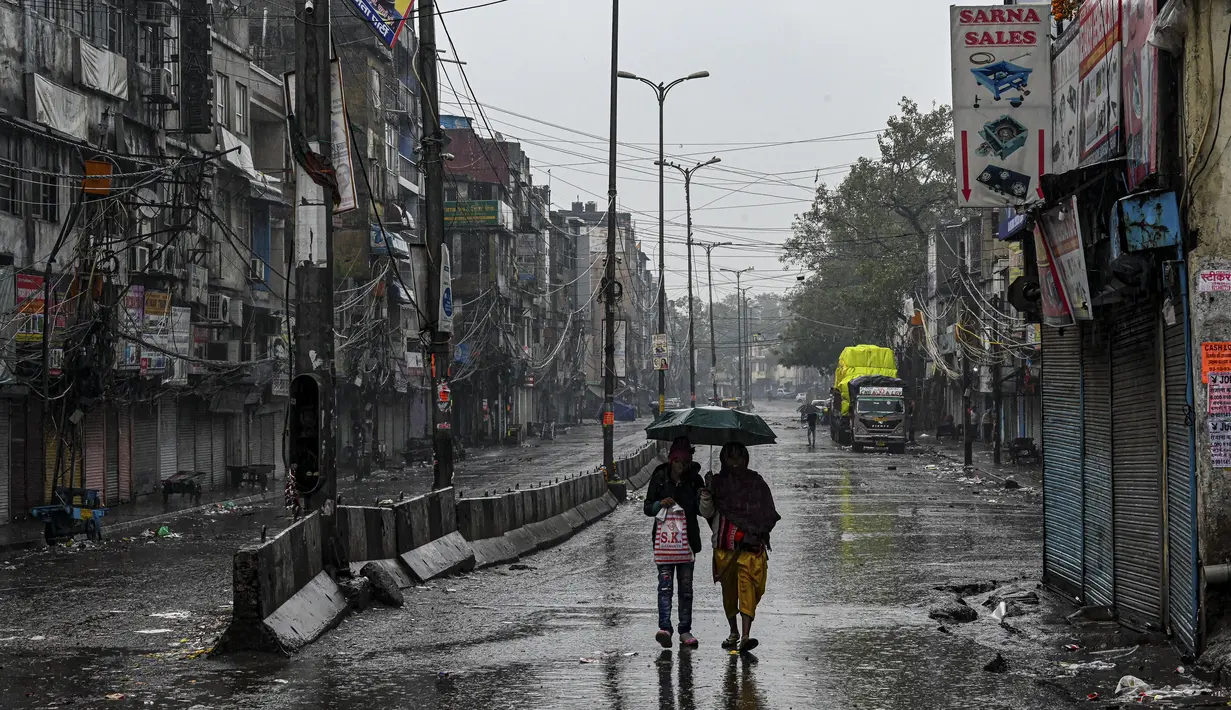 Para perempuan berjalan di sepanjang jalan yang sepi di Sadar Bazar selama jam malam akhir pekan di New Delhi, India, Sabtu (8/1/2022). Pihak berwenang memberlakukan jam malam selama akhir pekan di seluruh negara bagian Delhi saat jumlah kasus covid-19 kembali melonjak. (Prakash SINGH/AFP)