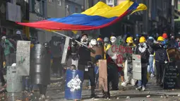 Seorang pria memegang bendera Kolombia saat bentrokan dengan polisi dalam protes antipemerintah di Bogota, Kolombia, Senin (28/6/2021). Protes dipicu oleh usulan kenaikan pajak atas layanan publik, bahan bakar, upah dan pensiun. (AP Photo/Fernando Vergara)