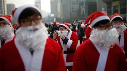 Seorang pria berpakaian seperti Santa Claus merapihkan jengotnya saat acara amal Natal di pusat kota Seoul, Korea Selatan, (24/12/2015). (REUTERS/Kim Hong-Ji)