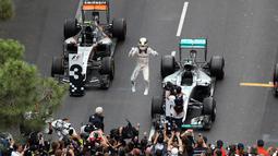 Pembalap Lewis Hamilton melakukan selebrasi di dalam sirkuit usai berhasil menjuarai Grand Prix di Monaco, (29/5). Ditempat kedua  pembalap Red Bull Daniel Ricciardo dan pembalap Force India, Sergio Perez, di tempat ketiga. (AFP PHOTO/Valery Hache)