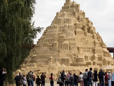 Seniman saat menyelesaikan istana pasir di Landschaftspark di Duisburg, Jerman , (1/9). Seniman dari Duisburg burusaha meraih Guinness Book of World Records dengan membuat istana pasir tertinggi yang pernah ada. (Marcel Kusch / dpa via AP)