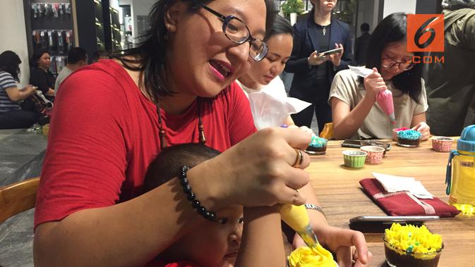 Seorang ibu yang mendampingi anaknya menghias kue saat acara peluncuran buku Leah Choy. (dok. Liputan6.com/Esther Novita Inochi)