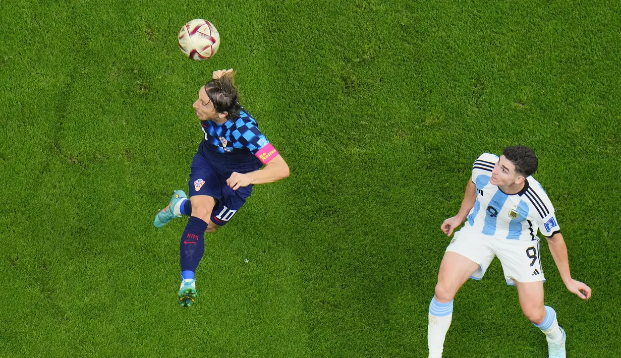Gelandang Kroasia, Luka Modric berebut bola udara dengan penyerang Argentina, Julian Alvarez selama pertandingan semifinal Piala Dunia 2022 di Stadion Lusail di Lusail, Qatar, Rabu (14/12/2022). Argentina berhasil lolos ke final setelah menang telak atas Kroasia dengan skor 3-0. (AP Photo/Hassan Ammar)