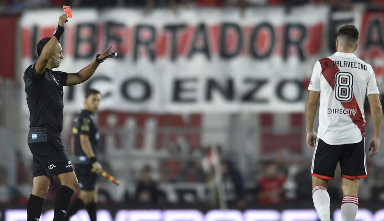 Wasit, Dario Herrera (kiri) memberikan kartu merah kepada pemain River Plate, Agustin Palavecino dalam laga yang bertajuk Superclasico tersebut. Sebanyak tujuh kartu merah harus dikeluarkan Dario Herrera dari saku celananya sebagai hukuman untuk tiga pemain River Plate dan empat pemain Boca Junior. (AP Photo/Gustavo Garello)