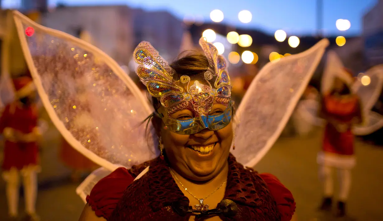 Seorang wanita mengenakan topeng dan kostum peri menari saat mengikuti parade tahunan di La Paz, Bolivia (24/11). Parade menyambut datangnya Natal ini selalu digelar setiap tahunnya. (AP Photo/Juan Karita)