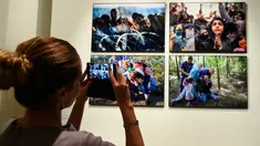 Pengunjung mengambil foto saat pameran karya fotografer Agence France-Presse (AFP) mengenai krisis migrasi di Eropa di pusat seni Bozar di Brussels (3/5). Pameran ini berjudul "Puting a Face on the Invisibles. (AFP Photo/John Thys)