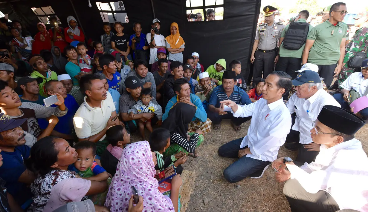 Presiden Joko Widodo atau Jokowi bersama Gubernur NTB Tuan Guru Bajang (TGB) Zainul Majdi berbincang dengan warga saat mengunjungi korban gempa di Desa Madayin, Sambelia, Lombok Timur, NTB, Senin (30/7). (Agus Suparto/Indonesian Presidential Palace/AFP)