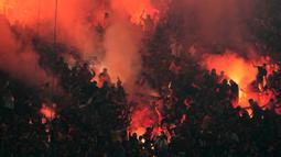 Para suporter Galatasaray menyalapan suar dalam laga lanjutan Liga Super Turki 2025/2026 antara Fenerbahce melawan Galatasaray di Chobani Stadium, Istanbul, Turki, Senin (01/12/2025) waktu setempat. (AP Photo/Khalil Hamra)