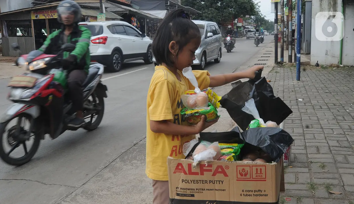 Seorang anak mengambil mi instan dan telur gratis di Jalan Raya Cibubur-Bojong Kulur, Bogor, Kamis (9/4/2020). Di beberapa pinggir jalan Kawasan Jabotabek saat ini banyak aksi solidaritas oleh warga dengan menyediakan bahan makanan gratis di tengah pandemi virus corona. (merdeka.com/Arie Basuki)