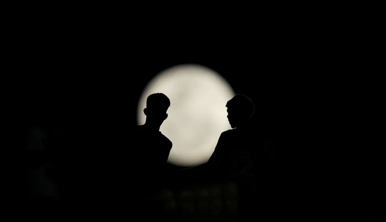 Suporter menyaksikan supermoon di atas stadion Defensores del Chaco selama pertandingan sepak bola leg pertama babak 16 besar Copa Sudamericana antara Libertad Paraguay dan Fortaleza Brasil di Asuncion, Paraguay, Selasa, 1 Agustus 2023. (AP Photo/Jorge Saenz)