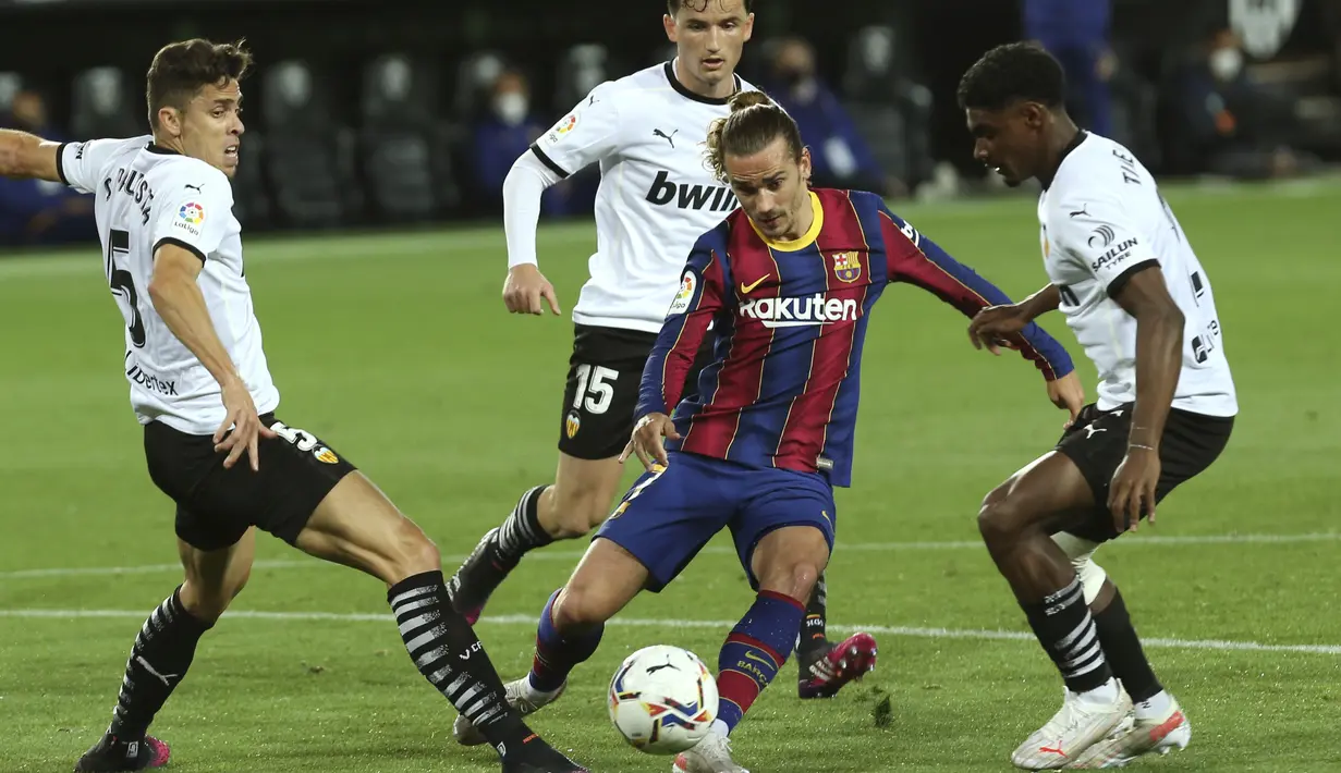 Penyerang Barcelona, Antoine Griezmann berusaha melewati para pemain Valencia pada pertandingan La Liga Spanyol di stadion Mestalla, Senin (3/5/2021). Kemenangan ini menjaga peluang juara Barcelona musim ini. Mereka masih ada di peringkat ketiga dengan 74 poin. (AP Photo/Alberto Saiz)