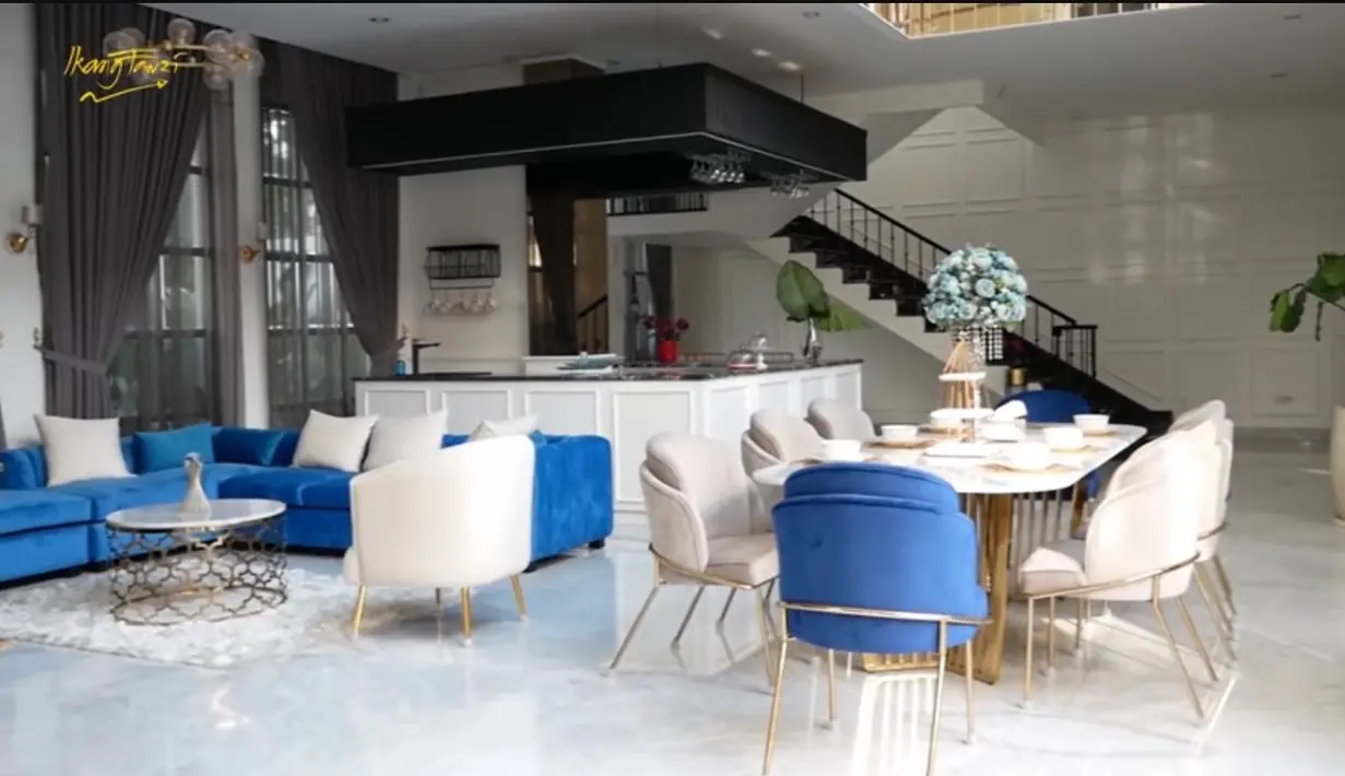 Ruangan tampak sangat luas dan tidak banyak pembatas. Ruang makan dengan meja marmer putih dan kursi putih berjejer. Ada juga sofa warna biru. Diruang ini juga ada mini bar. [Youtube/Ikang Fawzi Official]