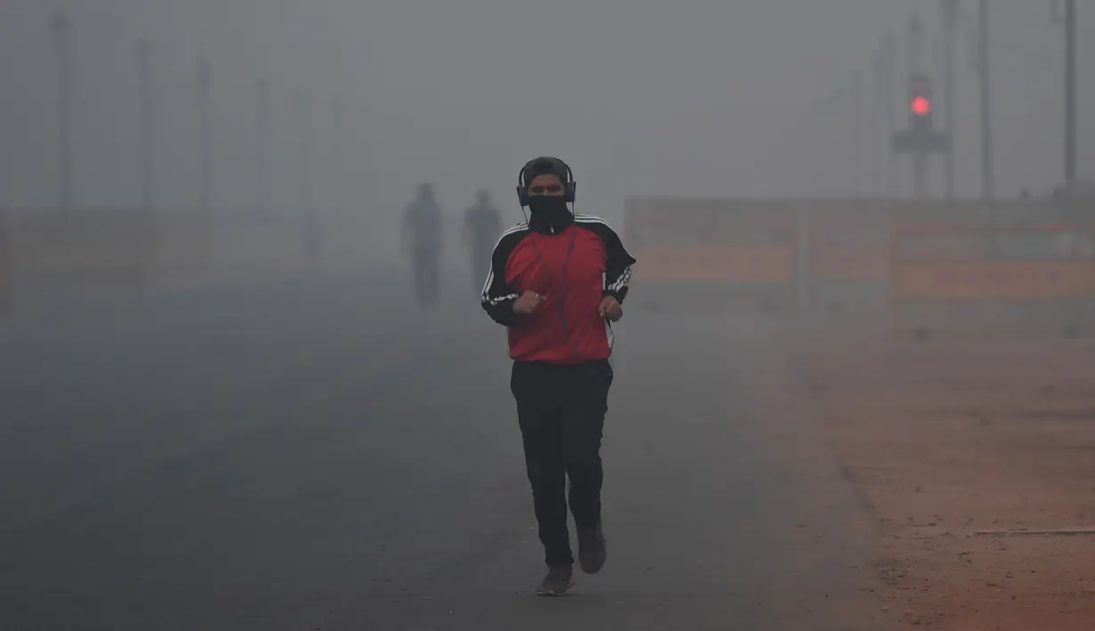 Pejalan kaki berolahraga di tengah kondisi kabut asap tebal di New Delhi (2/11). Tingkat kabut melonjak selama musim dingin di Delhi, ketika kualitas udara melampaui tingkat aman Organisasi Kesehatan Dunia. (AP Photo/Money Sharma)