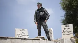 Seorang petugas polisi perbatasan Israel berdiri di tepi kuburan saat dia menyaksikan jemaah tiba untuk sholat Jumat pertama selama bulan suci Ramadhan di Masjid Kubah Batu di Kota Tua Yerusalem, Jumat (16/4/2021).  (AP Photo/Maya Alleruzzo)