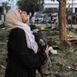 Seorang wanita bereaksi sambil memegang bantal ketika dia berdiri di tengah puing-puing di luar lokasi rumah sakit Ahli Arab di Gaza tengah pada 18 Oktober 2023. (MAHMUD HAMS/AFP)