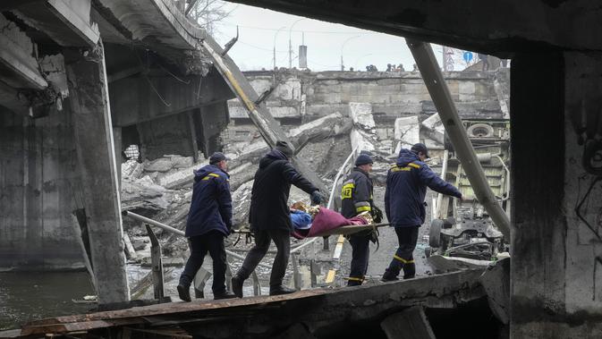 Petugas penyelamat Ukraina membawa seorang wanita tua di bawah jembatan yang hancur di Irpin, dekat Kyiv, Ukraina, Jumat, 1 April 2022. Sejak Rusia menginvasi Ukraina pada 24 Februari 2022, kini perang yang berkecamuk memasuki hari ke-37. (AP Photo /Efrem Lukatsky)