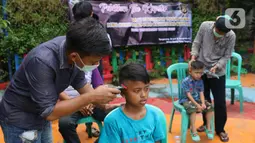 Seorang anak sedang dicukur rambutnya oleh remaja yang tengah mengikuti pelatihan cukur rambut di Tangerang, Banten, Rabu (18/11/2020). Pelatihan tersebut bertujuan agar masyarakat dapat memiliki kemampuan dan keterampilan. (Liputan6.com/Angga Yuniar)