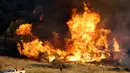 Petugas damkar berusaha memadamkan kobaran api yang membakar lahan di daerah Kalyvia, dekat Athena, Yunani, Senin (31/7). Lahan luas berjarak 30 kilometer dari kota Athena itu terbakar pada malam waktu setempat. (AP/Thanassis Stavrakis)