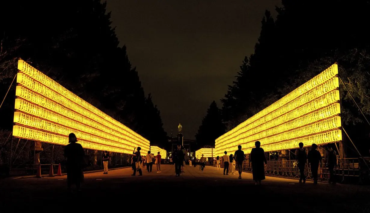 Para pengunjung berjalan melewati lentera kertas saat Festival Mitama di Kuil Yasukuni, Tokyo, Jepang, Rabu (14/7/2021). Festival Mitama dirayakan sejak 1947 untuk menghormati jiwa para arwah yang diabadikan serta tentara yang gugur dari perang Jepang di masa lalu. (BEHROUZ MEHRI/AFP)