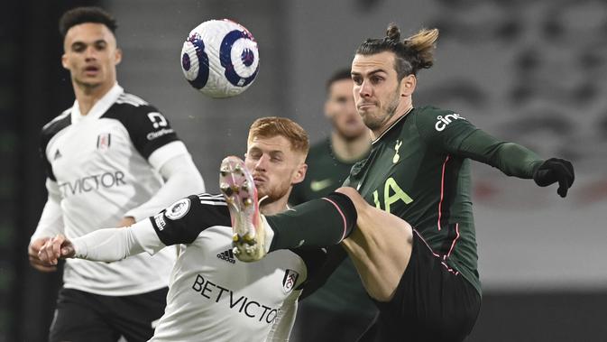 Gelandang Fullham, Harrison Reed berebut bola dengan penyerang Tottenham Hotspur, Gareth Bale pada pekan ke-27 Liga Inggris di Craven Cottage, Jumat (5/3/2021) dini hari WIB. Tottenham Hotspur unggul 1-0 atas Fullham lewat gol bunuh diri Tosin Adarabioyo. (Neil Hall/Pool via AP)