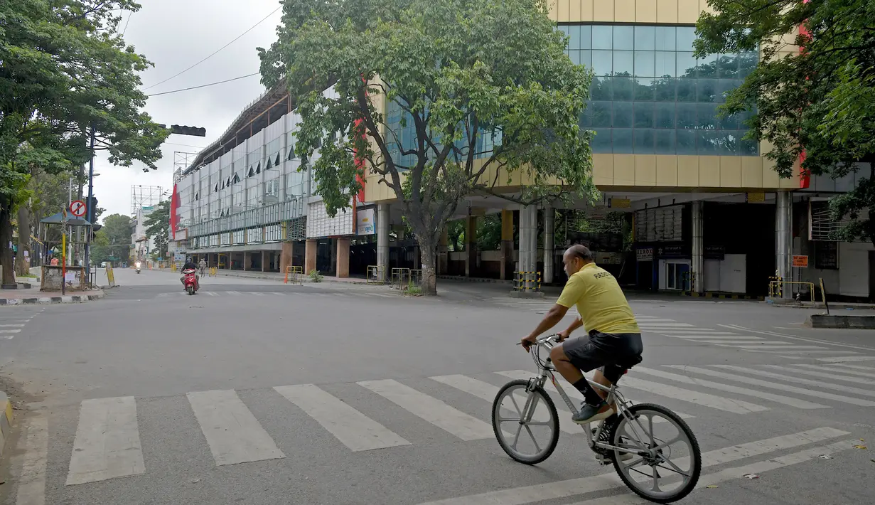 Seorang pria bersepeda di depan kios bus Jayanagar yang sepi saat pemberlakukan lockdown di Bangalore, Rabu (15/7/2020). Pusat IT India, Bangalore, kembali memberlakukan lockdown selama seminggu dimulai dari 14 Juli 2020 untuk menahan lonjakan kasus Covid-19 yang meningkat. (Manjunath Kiran/AFP)