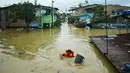 Seorang penyelamat mengarungi air banjir akibat hujan lebat semalam di Medan, Sumatera Utara (4/12/2020). Ketinggian air mulai 50 Cem hingga 1 meter lebih. (AFP/Rahmad Suryadi)