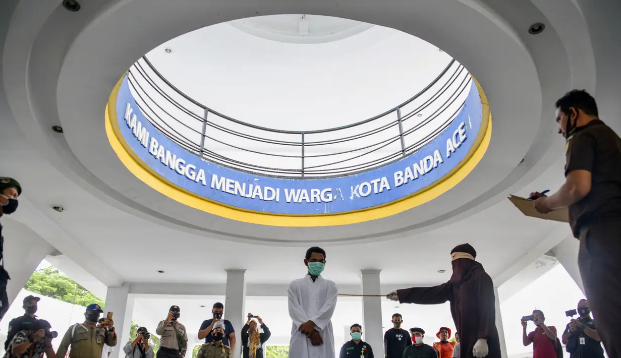 Seorang pria saat dihukum cambuk dengan tongkat rotan oleh anggota polisi Syariah di sebuah gedung umum di Banda Aceh (24/9/2020). Aceh adalah satu-satunya wilayah di Indonesia yang berpenduduk mayoritas Muslim terbesar di dunia yang menerapkan Hukum Islam. (AFP/Chaideer Mahyuddin)