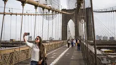 Turis mengambil foto di Jembatan Brooklyn, AS, Rabu (1/3). Menurut NYC & Co, larangan perjalanan yang sempat diucapkan Presiden Donald Trump telah menghambat minat pariwisata internasional. (Drew Angerer / Getty Images / AFP)