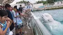 Ekspresi sejumlah pengunjung saat di semprotkan air oleh beluga dalam atraksi musim panas di akuarium Laut Paradise Hakkeijima di Yokohama, Tokyo (16/7). (AFP Photo/Kazuhironogi)