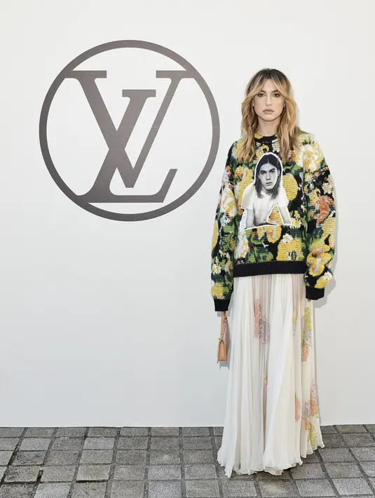 Putri Steve Jobs, Eve Jobs juga hadir dengan penampilan yang lebih vibrant. Ia tampil semi kasual dengan memadukan floral sweater dengan rok tulle bermotif bunga. (Louis Vuitton)