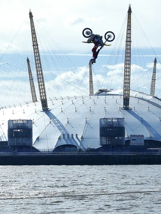 Aksi backflip Travis Pastrana dengan sepeda motornya saat berada di atas Sungai Thames, London, Kamis (5/10). Pastrana mampu melewati jarak antarkapal tongkang sepanjang 23 meter. (AP Photo/Alastair Grant)