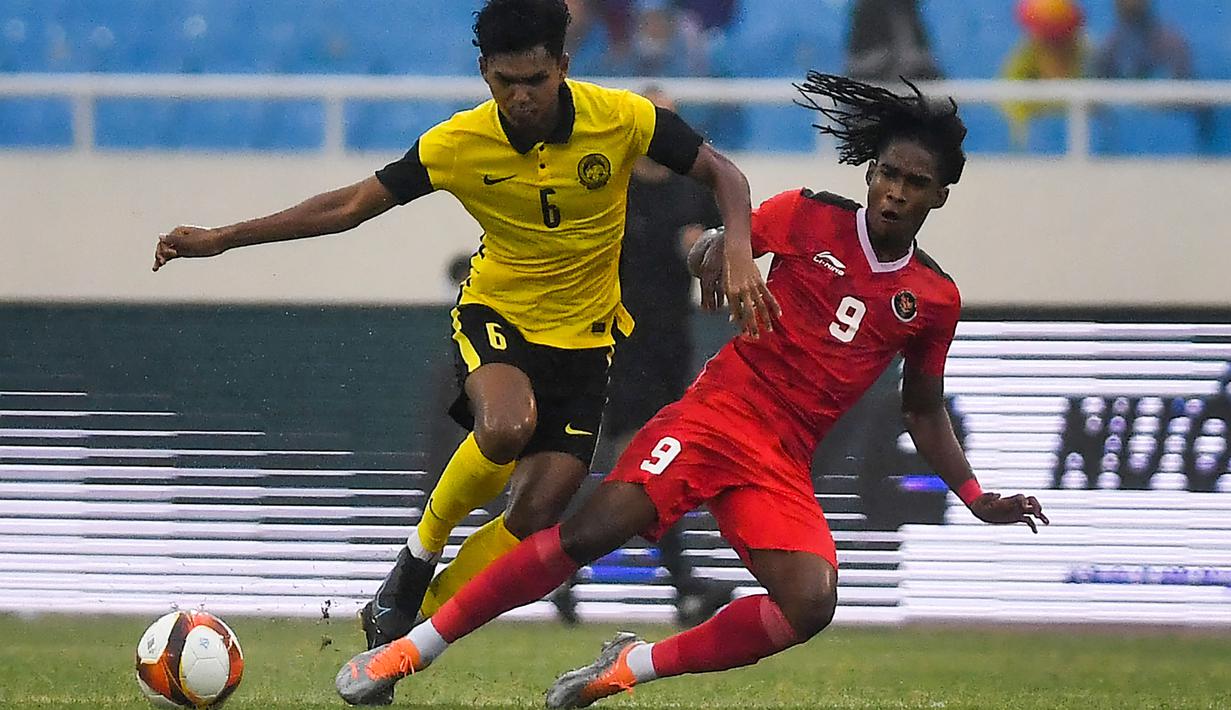 <p>Penyerang Timnas Indonesia U-23, Ronaldo Joybera R Junior berebut bola dengan bek Malaysia, Muhammad Azam bin Azmi Murad dalam pertandingan perebutan medali perunggu SEA Games 2021 di Stadion My Dinh, Minggu (22/5/2022). Indonesia ditahan imbang 1-1 dan menang 4-3 di adu penalti. (AFP/Ye Aung Thu)</p>