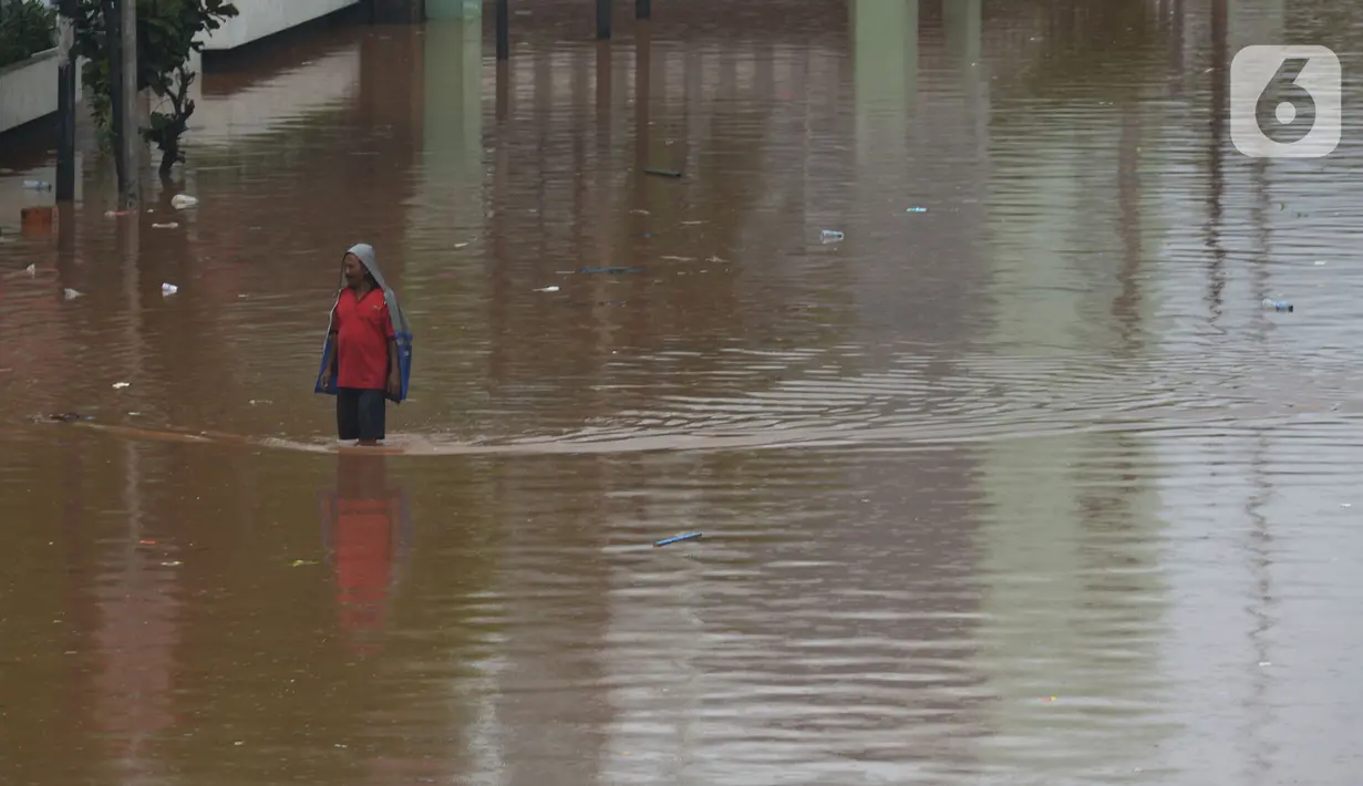 Warga melintasi banjir di Jalan Raya Daan Mogot, Jakarta, Rabu (1/1/2020).  Hujan yang turun saat malam pergantian tahun baru 2019-2020 menyebabkan sejumlah titik jalan terputus di kawasan Grogol terendam banjir. (merdeka.com/Imam Buhori)