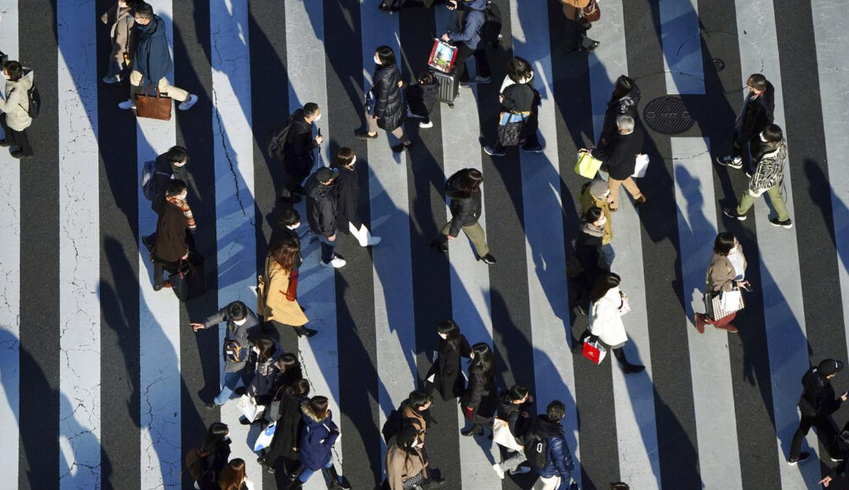 Orang-orang yang memakai masker untuk membantu mengekang penyebaran COVID-19 menyeberangi jalan di Tokyo, Jepang, 29 Desember 2021. Kepala Rumah Sakit Pusat Sumida Dr Kuniaki Kojima memprediksi jumlah kasus COVID-19 di Jepang akan melonjak drastis pada Januari 2022. (AP Photo/Eugene Hoshiko)