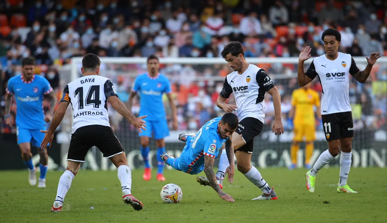Pemain depan Atletico Madrid, Angel Correa (tengah) ditekel oleh bek Valencia, Hugo Guillamon (kedua kanan) selama pertandingan lanjutan La Liga Spanyol di stadion Mestalla di Valencia (8/11/2021). Valencia bermain imbang atas Atletico Madrid 3-3. (AFP/Jose Jordan)