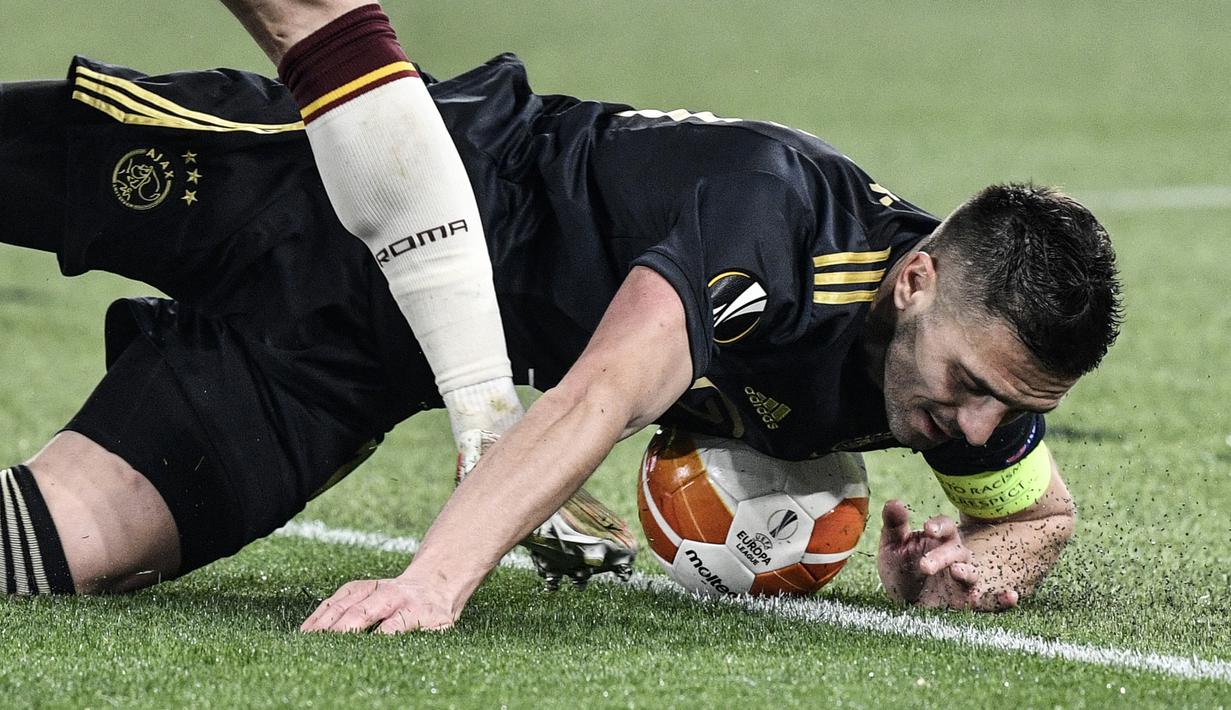 Striker Ajax Amsterdam, Dusan Tadic terjatuh usai ditekel pemain AS Roma dalam laga leg kedua perempatfinal Liga Europa 2020/2021 di Olimpico Stadium, Roma, Kamis (15/4/2021). Ajax bermain imbang 1-1 dengan AS Roma. (AFP/Filippo Monteforte)