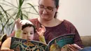 Yusuf Kamel (2) dibacakan buku ibunya, Nadia Chaouch  sambil menunggu buka puasa dirumahnya di Seattle (28/4/2020). Keluarga itu, seperti Muslim lainnya selama pandemi, melaksanakan bulan puasa Ramadan dengan doa dan refleksi dirumahnya daripada bertemu komunitas dan ke masjid. (AP/Elaine Thompson)