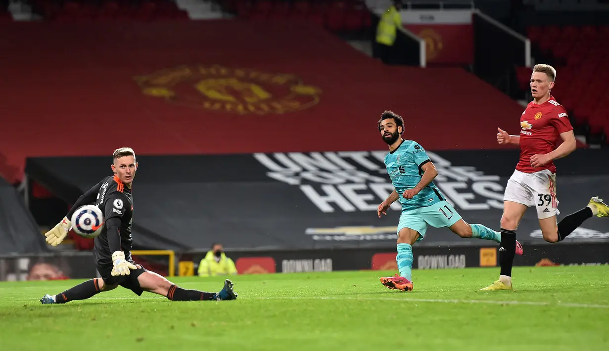 Gelandang Liverpool, Mohamed Salah (tengah) melepaskan tendangan yang berbuah gol keempat timnya ke gawang Manchester United dalam laga lanjutan Liga Inggris 2020/2021 pekan ke-35 di Old Trafford, Kamis (13/5/2021). Liverpool menang 4-2 atas Manchester United. (AFP/Peter Powell/Pool)