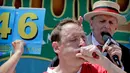 Ekspresi Joey Chestnut saat menyantap dua hot dog dalam Kontes Makan Internasional Nathan, di New York, AS (4/7). Joey Chestnut hanya kalah sekali dari Matt Stonie pada 2015. (AP Photo/Bebeto Matthews)